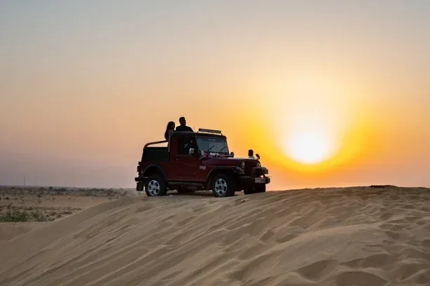 Open jeep driving over sand dunes near Jaisalmer
